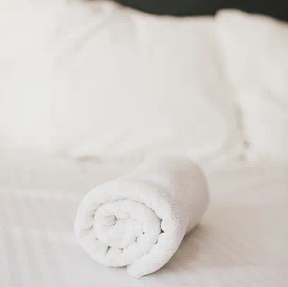 Asciugamano arrotolato su un letto rifatto