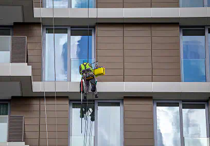 Operatore sospeso su fune mentre pulisce i vetri di un edificio