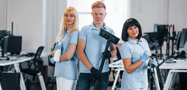 Squadra di addetti alle pulizie in un ufficio, con aspirapolvere e detergenti