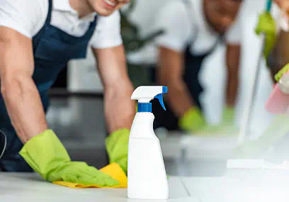 Addetti al lavoro su un piano di lavoro con detergente spray